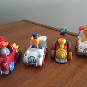 1981/1983 Sesame Street die-cast cars. Ernie, Cookie Monster/Hasbro and(Big Bird/Playskool.  Lot of four (4) cars. Fair - Good condition.