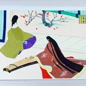 Può includere: Stampa xilografica giapponese raffigurante due figure in abiti tradizionali. Una figura indossa una veste verde e un cappello nero, l'altra suona il koto. L'opera presenta un albero di prugne e bambù, incorniciata in bianco.