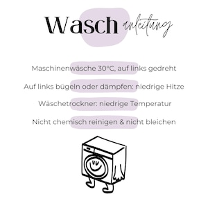 Pode incluir: Fundo branco com o texto alem&atilde;o "Waschanleitung" em escrita preta, acima das instru&ccedil;&otilde;es de lavagem. As instru&ccedil;&otilde;es incluem lavar na m&aacute;quina a 30&deg;C, passar a ferro em temperatura baixa e n&atilde;o limpar a seco. Uma m&aacute;quina de lavar roupa de desenho animado est&aacute; na parte inferior.