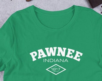 Peut inclure: T-shirt à manches courtes de couleur verte avec un texte blanc qui dit "Pawnee Indiana 1817" dans un losange.