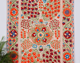 May include: A cream-coloured tapestry featuring a detailed floral pattern in shades of red, orange, green, and blue. The design incorporates pomegranates, flowers, and geometric shapes.
