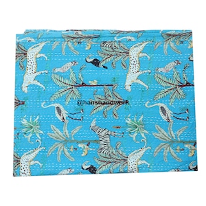 May include: A blue kantha quilt featuring a white and black zebra, leopards, and birds printed on it. The quilt has a hand-stitched design and is made of cotton.