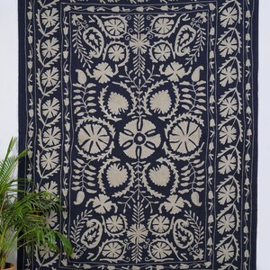 Puede incluir: Tapiz azul marino con un dise&ntilde;o floral beige. El tapiz presenta un medall&oacute;n floral central rodeado de flores y hojas estilizadas. El borde es un patr&oacute;n floral repetitivo. Este textil es adecuado para la decoraci&oacute;n de paredes.