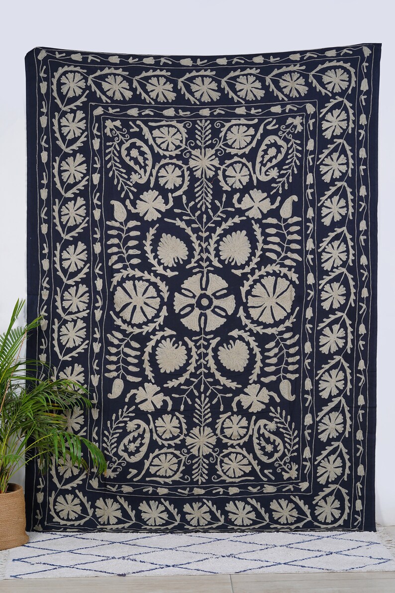 Puede incluir: Tapiz azul marino con un dise&ntilde;o floral beige. El tapiz presenta un medall&oacute;n floral central rodeado de flores y hojas estilizadas. El borde es un patr&oacute;n floral repetitivo. Este textil es adecuado para la decoraci&oacute;n de paredes.
