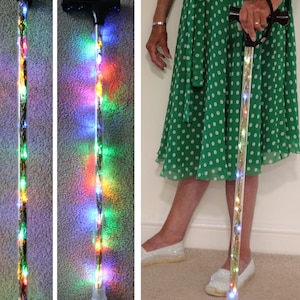 May include: A clear walking cane with embedded colorful LED lights. The cane has a black handle and a clear tip. The lights are visible along the entire length of the cane, creating a decorative and functional mobility aid.