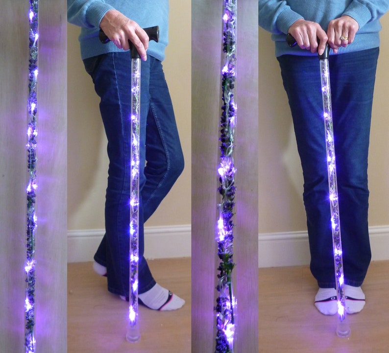May include: A clear, illuminated walking cane with purple LED lights and decorative elements. The cane has a black handle and a clear base. The lights are arranged along the length of the cane, creating a glowing effect. The cane is approximately 36 inches long.