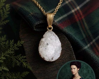 May include: A teardrop-shaped white druzy pendant necklace with a gold-toned metal setting and a matching gold-toned chain. The pendant features a textured, crystalline surface and is suspended from a delicate link chain.