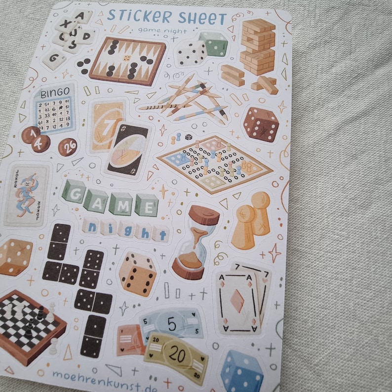K&ouml;nnte beinhalten: Eine Sticker-Tafel mit verschiedenen Illustrationen zum Thema Spiele, darunter W&uuml;rfel, Dominosteine, Spielkarten, eine Bingokarte, ein Spielbrett und die Worte "GAME NIGHT".