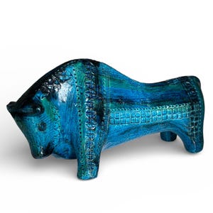 Op de afbeelding: Een keramische sculptuur van een stier in blauwe en turquoise tinten. De stier heeft een textuur met gedetailleerde patronen. Een decoratief item, waarschijnlijk voor in huis.
