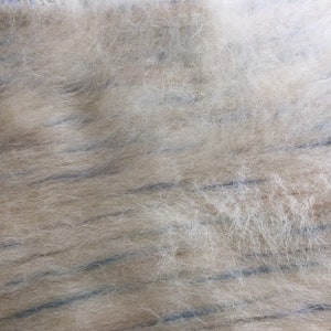 May include: Close-up of a light brown fuzzy fabric with thin, dark blue stripes running horizontally across the surface.