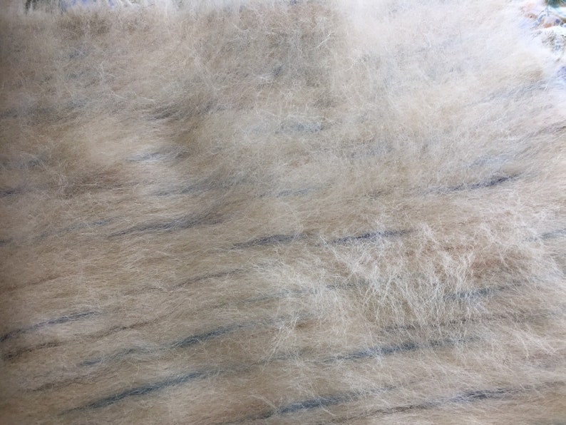 May include: Close-up of a light brown fuzzy fabric with thin, dark blue stripes running horizontally across the surface.