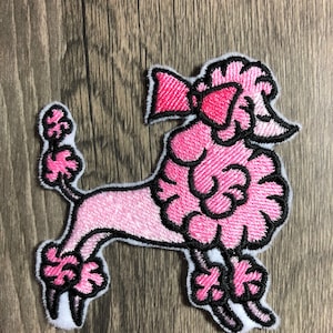 Op de afbeelding: Roze geborduurde poedelpatch met een zwarte omtrek en een roze strik. De poedel staat op zijn achterpoten met zijn voorpoten omhoog.