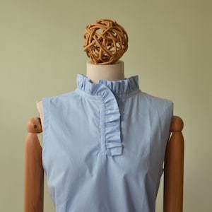 FIORDALISO top in light sky blue color, in pure cotton. High collar with mini rouche and cut on the front.