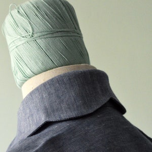 Op de afbeelding: Een blauw denim overhemd met een grote kraag. De kraag is omlaag gevouwen en heeft een gebogen vorm. Het overhemd is gemaakt van een textuur stof.