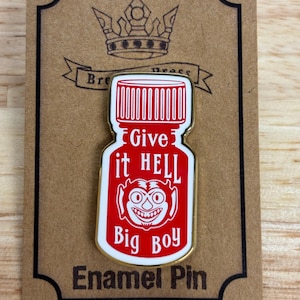 May include: A red and white enamel pin shaped like a bottle with the text "Give it HELL Big Boy" and a cartoon devil face.
