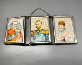 May include: A set of three small framed portraits of a man and two women in military uniforms. The frames are connected by a chain and each frame has the text "Made in Germany" printed on it.