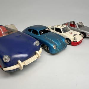 Könnte beinhalten: Vier Spielzeugautos, darunter ein blaues Cabriolet, ein blaues und weißes Sportwagen, ein weißes und rotes Sportwagen mit der Nummer "11" auf der Windschutzscheibe und ein silberner Sportwagen.