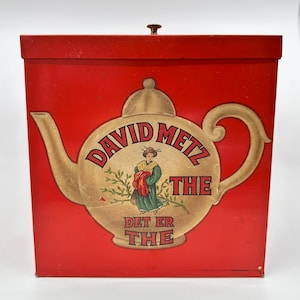 May include: Red metal tea tin with a lid and a graphic of a teapot with the text "David Metz The Det Er The" on the front.