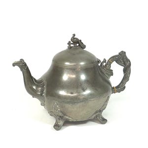 Grande teiera antica in peltro, decorata con pavone e serpente, risalente al 1900 circa.