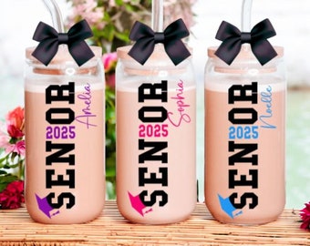 May include: Three glass jars with black bows and straws. Each jar has a black and white "Senior 2025" design with a graduation cap and a personalized name: Amelia, Sophia, and Noelle.
