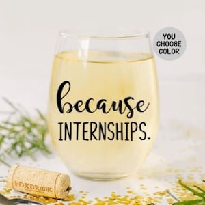 May include: A clear glass wine glass with the text "because internships." printed on it. The glass is filled with a light yellow liquid.