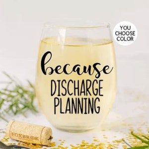 May include: A clear glass wine glass with the text "because discharge planning" printed on it. The glass is filled with a light yellow liquid.