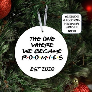 May include: White round Christmas ornament with black text that reads "The One Where We Became Roomies Est 2020".
