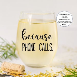 May include: A clear glass wine glass with white wine inside. The glass has a black vinyl decal that says "because phone calls."