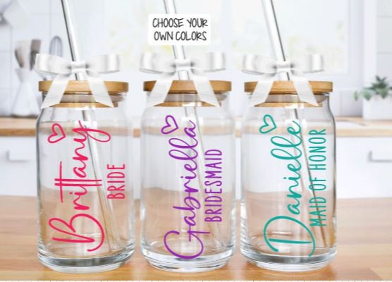 May include: Three glass jars with bamboo lids and straws. Each jar has a different name and title: "Brittany Bride", "Gabriella Bridesmaid", and "Danielle Maid of Honour".