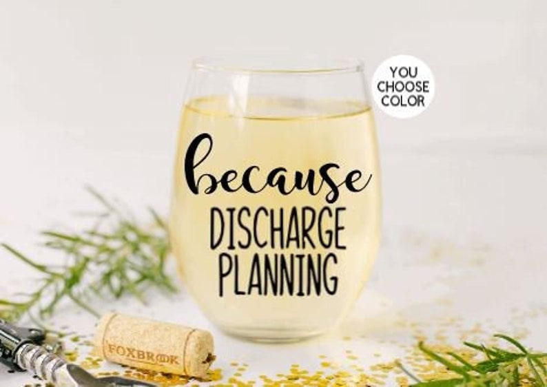 May include: A clear glass wine glass with the text "because discharge planning" printed on it. The glass is filled with a light yellow liquid.