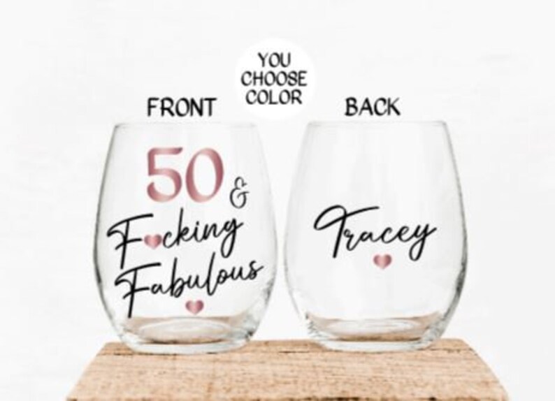 May include: Two clear stemless wine glasses with a rose gold design. The front glass says "50 & F*cking Fabulous" and the back glass says "Tracey".