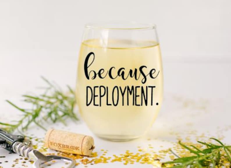 Pu&ograve; includere: Un bicchiere di vino in vetro trasparente con vino bianco al suo interno. Il bicchiere ha un adesivo in vinile nero che dice "because deployment."