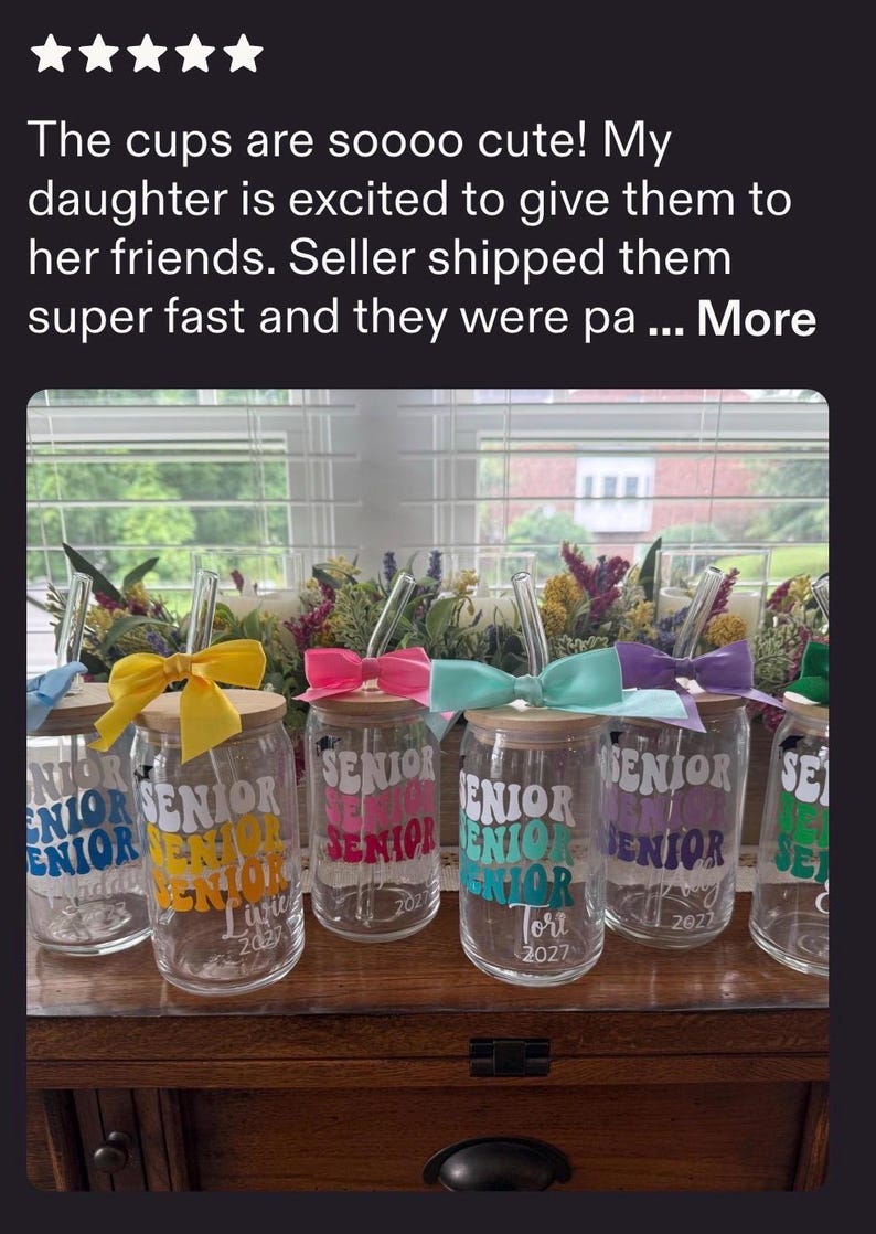 May include: A set of clear glass tumblers with bamboo lids and glass straws. Each tumbler features the word SENIOR printed in a wavy font in various colors, including yellow, pink, teal, purple, and green, with a matching satin bow tied to the straw.