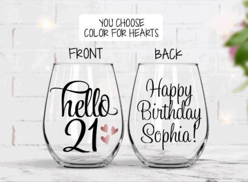 May include: Two stemless wine glasses with black script. One glass says "hello 21" with three pink hearts. The other says "Happy Birthday Sophia!" The text "You choose color for hearts" is above the glasses.