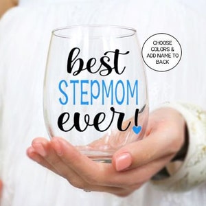 May include: A clear glass wine glass with the text "best stepmom ever!" in black lettering with a blue heart. The word "stepmom" is in blue lettering.