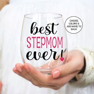 May include: A clear glass wine glass with the text "best stepmom ever!" in black and pink lettering. A small pink heart is next to the exclamation point.