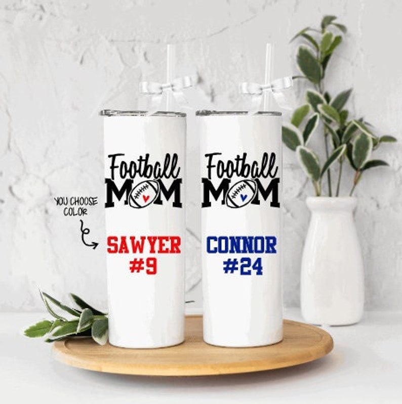 May include: Two white stainless steel tumblers with a football design and the text "Football Mom". The tumblers are personalized with the names "Sawyer #9" and "Connor #24".