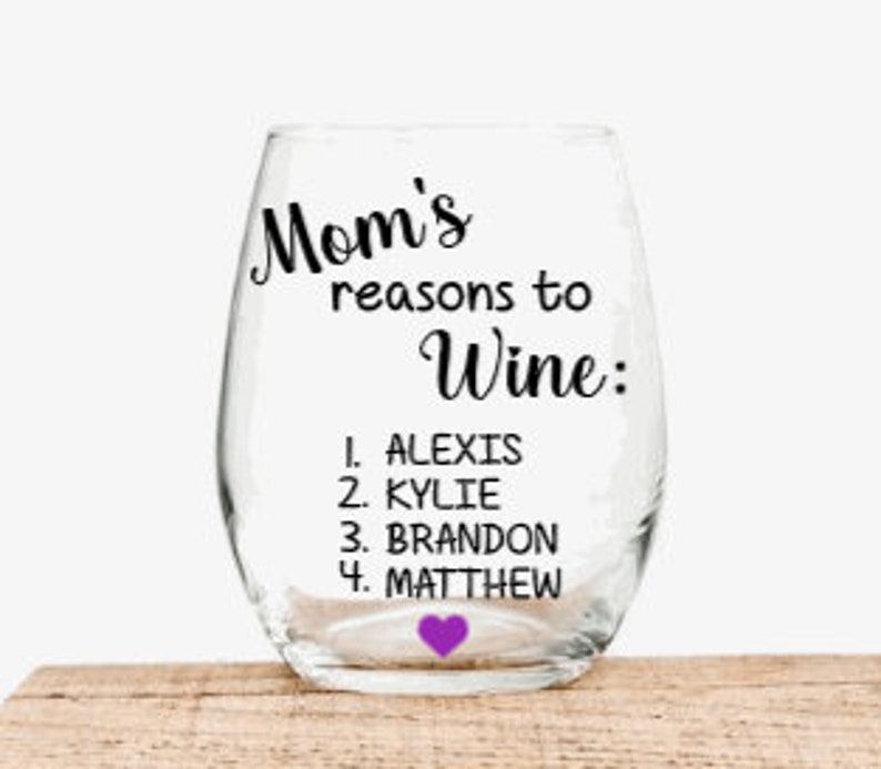 May include: A clear glass wine glass with the text "Mom's reasons to Wine:" and a list of names: Alexis, Kylie, Brandon, and Matthew. A small purple heart is at the bottom of the list.