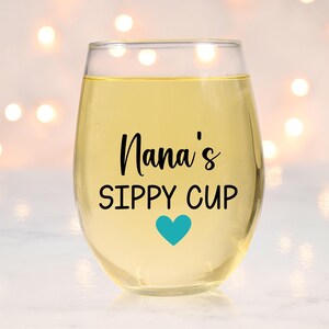 May include: A clear glass wine glass with the text "Nana's Sippy Cup" and a blue heart on the front.