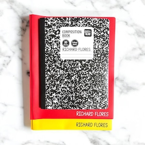 May include: A composition book with a black and white speckled cover, red spine, and yellow and red borders. The cover reads "COMPOSITION BOOK" and "RICHARD FLORES". The notebook has 80 college-ruled sheets.