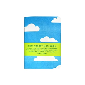 Puede incluir: Una libreta de bolsillo azul con un patrón de nubes blancas. La cubierta tiene una etiqueta verde que dice "RISO POCKET NOTEBOOK", "40 DOT GRID PAGES, ON RECYCLED PAPER", "RISO PRINTED WITH VEGETABLE-BASED INKS", "ASSEMBLED BY HAND IN THE U.S.A.", y "3.75" x 5.25"".