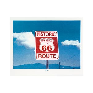 Peut inclure: Photographie d'un panneau routier vintage de la Route 66 au Nouveau-Mexique. Le panneau est rouge et blanc, avec les mots "Historic", "New Mexico", "U.S. 66 Route" imprimés dessus. Le fond est un ciel bleu avec des nuages blancs.