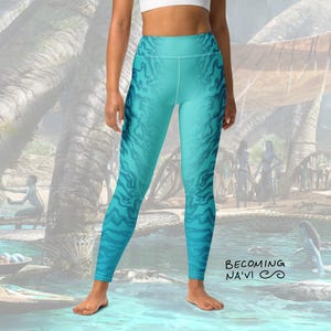 May include: Blue and teal leggings with a swirling pattern. The leggings have a high waist and are made of a stretchy, comfortable fabric. The leggings are printed with the text "Becoming Na'vi".