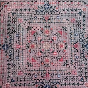 May include: A cross-stitch pattern for a cottage garden design. The pattern features a pink background with a black and white floral design. The title of the pattern is "The Cottage Garden" and it is part of the "Garden Labyrinth Collection" by Carolyn Manning Designs.
