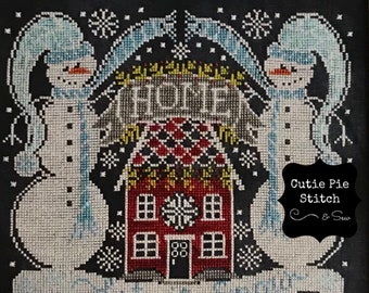May include: Cross stitch pattern featuring two snowmen standing on either side of a red house with a white roof. The house has a wreath on the door and the words "Home Sweet Home" above it. The snowmen are wearing blue scarves and hats. The background is black with white snowflakes.