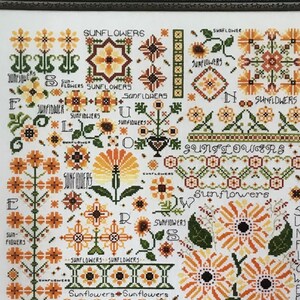 May include: A cross-stitch pattern featuring a variety of sunflowers in different colors and styles. The pattern includes the word "Sunflowers" repeated throughout, along with the words "Sun-Flowers" and "Sun Flower".