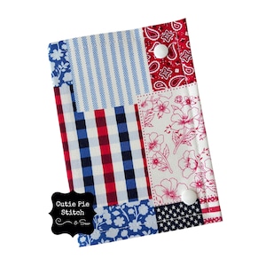 May include: A patchwork fabric item in red, white, and blue. It features floral, gingham, paisley, and striped patterns. The item is secured with two white buttons and has the text "Cutie Pie Stitch & Sew".