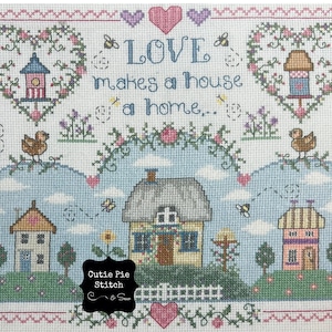 May include: Cross stitch pattern featuring a cottage with a thatched roof, surrounded by flowers and hearts. The text "LOVE makes a house a home..." is stitched above the cottage. The pattern is titled "Cutie Pie Stitch & Sew".