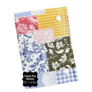 May include: A patchwork fabric item featuring a mix of patterns and colours, such as floral, striped, and gingham. Two white buttons secure the item. The text "Cutie Pie Stitch & Sew" is visible.