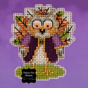 May include: Cross stitch pattern of a cute owl wearing a purple coat and surrounded by fall leaves. The pattern is titled "Cutie Pie Stitch & Sew".
